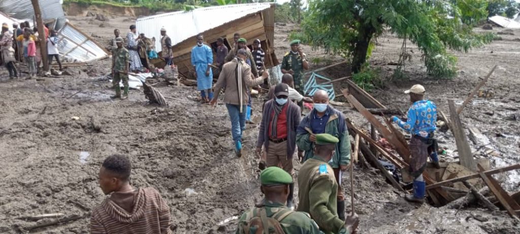 Des autorités avec des personnes procédant à la recherche des corps enfouis dans la boue et les decombres