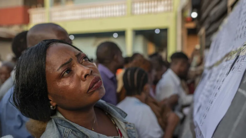 une femme scrute avec intensité la liste des votants dans l'une des stations de vote des élections en République démocratique du Congo en 2023