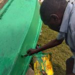 Sous un soleil accablant, le regard artistique unique de Muhindo Mupira Vincent, peint une pirogue de pêche à la plage de Vitshumbi vulgairement connue sous le sobriquet " Kaingini"